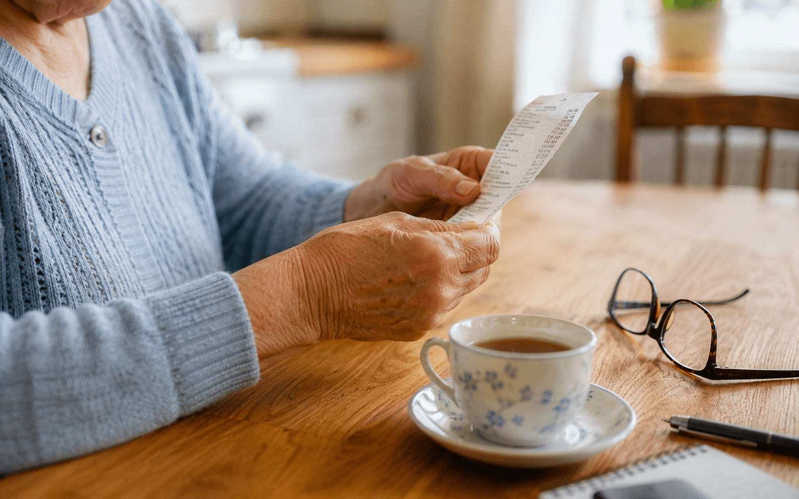 Close-up of hands with a receipt or invoice and a cup of tea, ordinary and unstressed