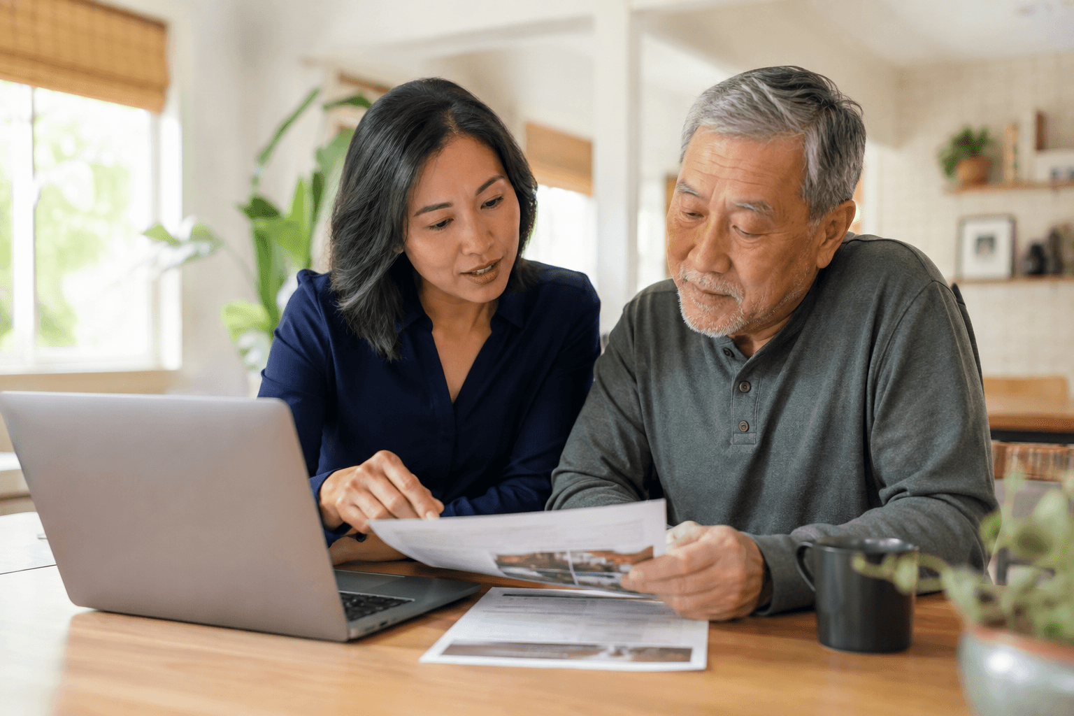 Adult child and parent looking at something together on a laptop or brochure